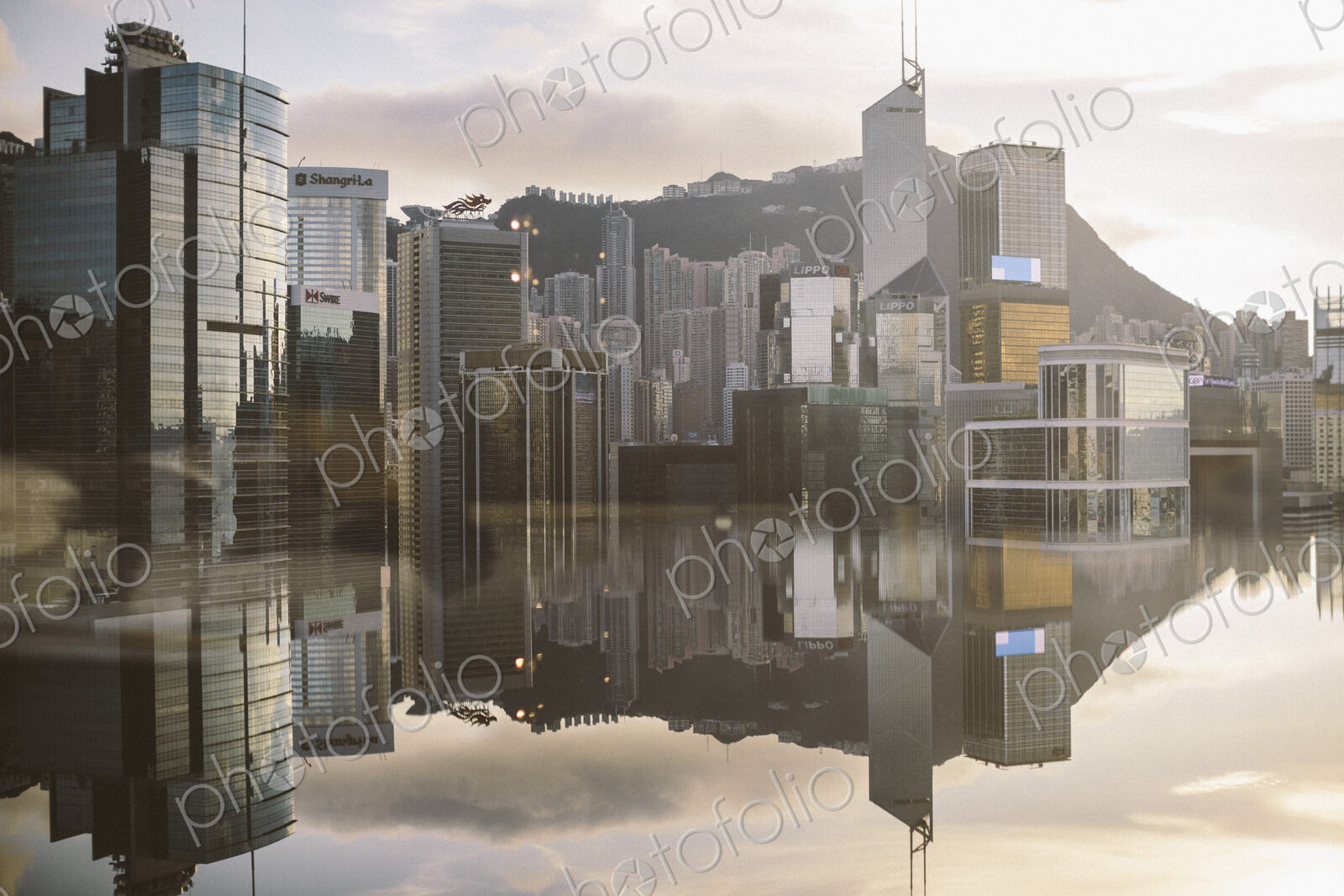 Cityscape with modern skyscrapers reflected in calm sea.