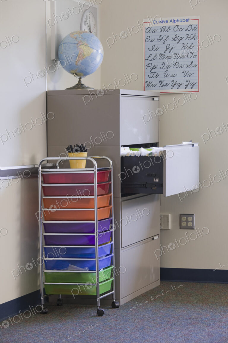 Classroom filled with equipment including filing cabinet, globe, and handwriting poster.