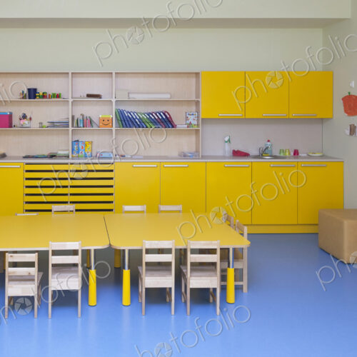 Classroom in a kindergarten school, yellow furniture and tables and blue floor.