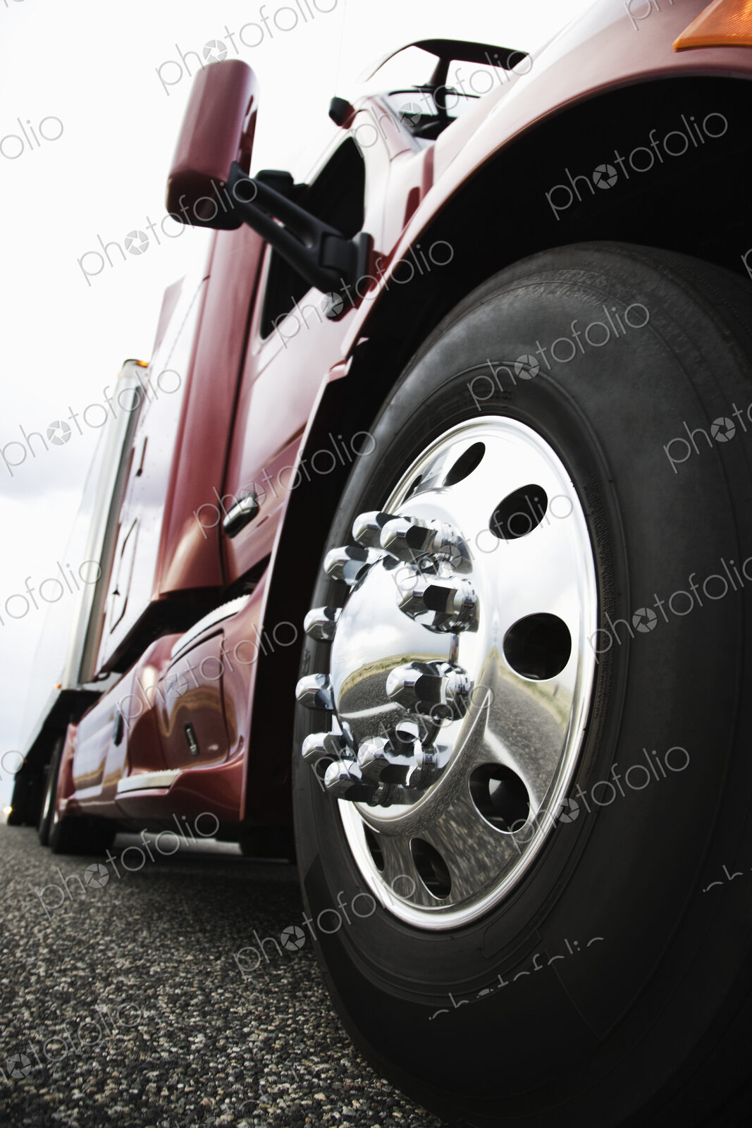 Close up 3/4 angle view of the cab and front tire on a commercial truck on the road at…