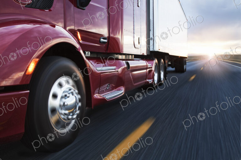 Close up 3/4 angle view of the cab and front tire on a commercial truck on the road at…