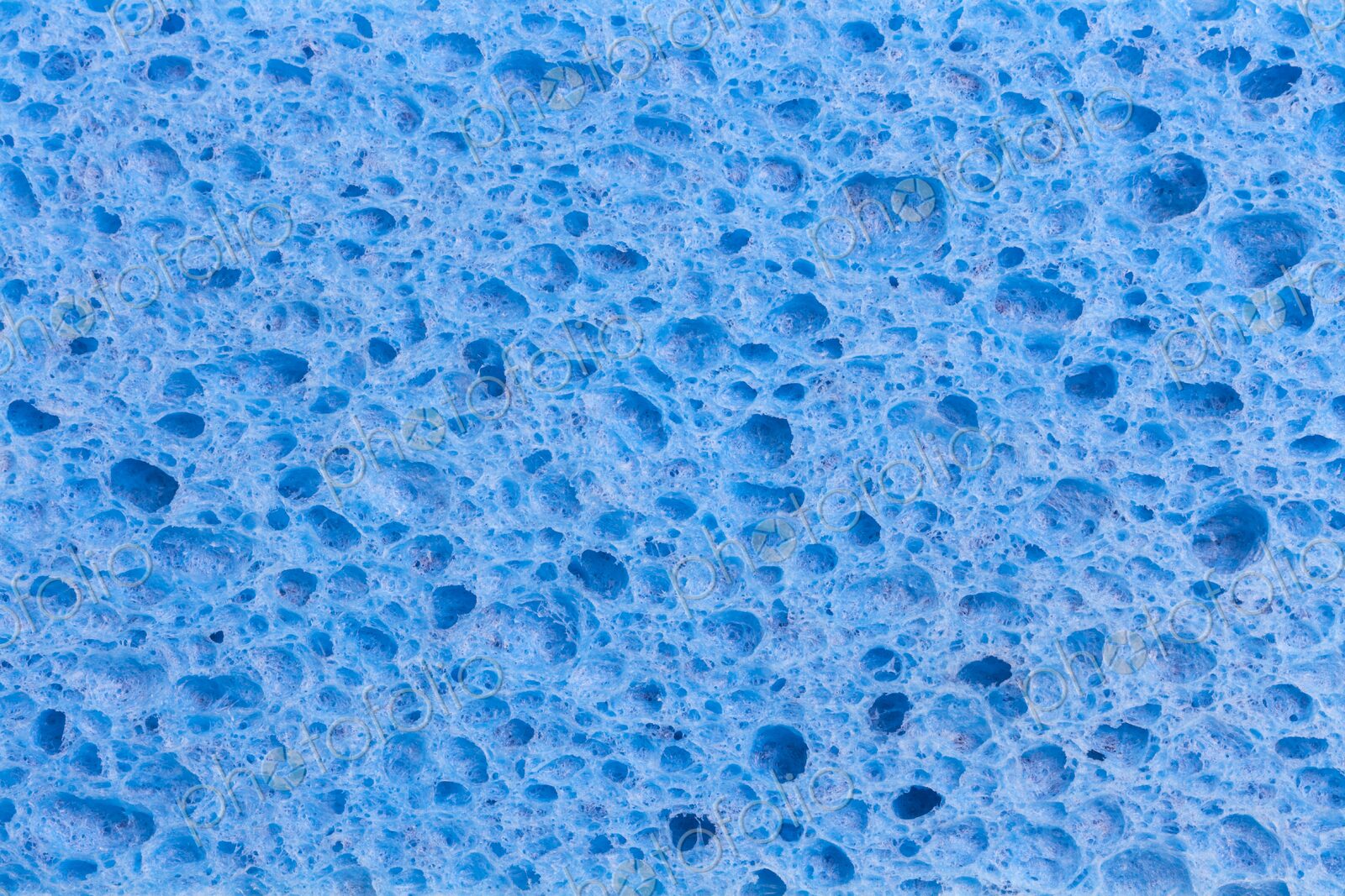 Close up full frame of a blue cleaning sponge with a pitted porous surface, a plastic…
