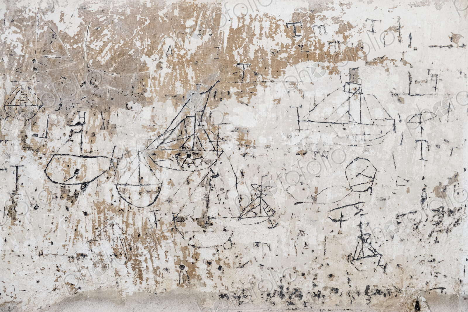 Close up of 18th century graffiti of sailboats on a wall.