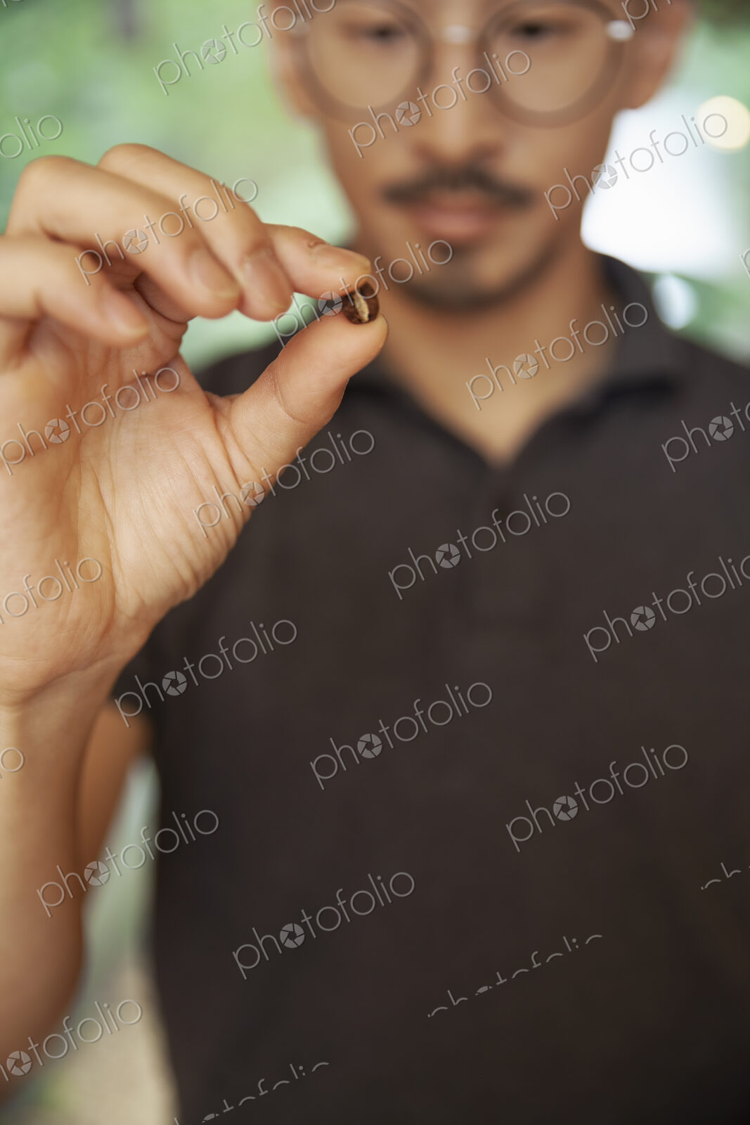 Close up of Japanese man holding roasted coffee bean.