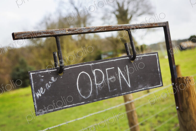 Close up of 'Open' sign on a fence at a farm shop.