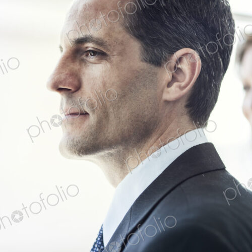 Close-up of a Caucasian businessman looking out the widow of a conference centre lobby.