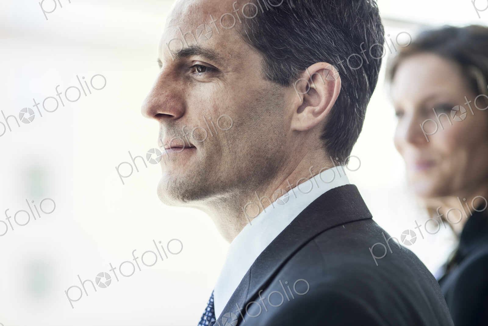 Close-up of a Caucasian businessman looking out the widow of a conference centre lobby.