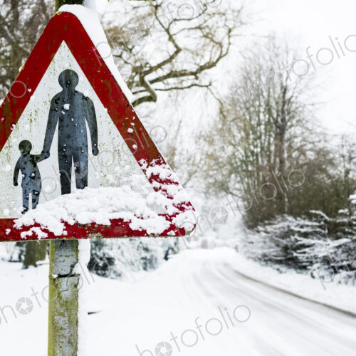 Close up of a 'Pedestrians in road' sign on side of snow-covered rural road. Close up of a 'Pedestrians in road' sign on side of snow-covered rural road.