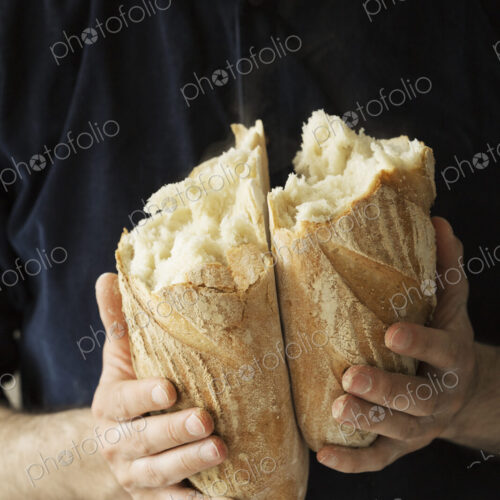Close up of a baker holding two freshly baked loaves of bread.