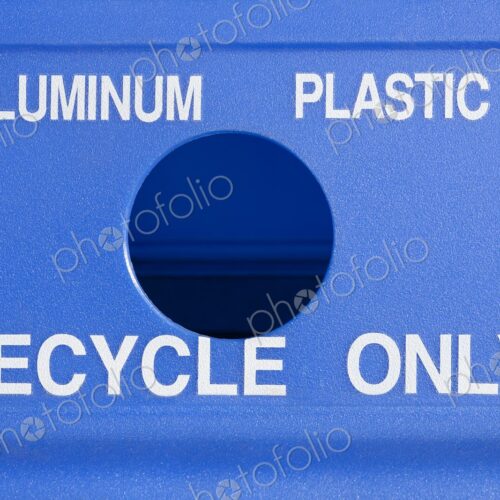 Close-up of a blue recycling bin marked for aluminum and plastic with a circular opening.