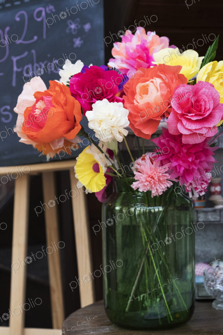 Close up of a bunch of colourful handcrafted fabric flowers in a vase.