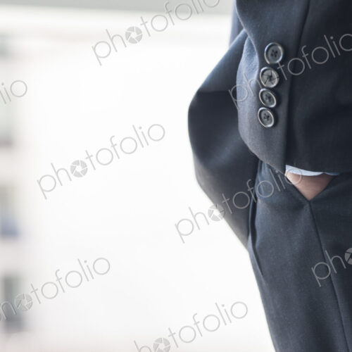 Close-up of a businessman's hand in a suit pants pocket.