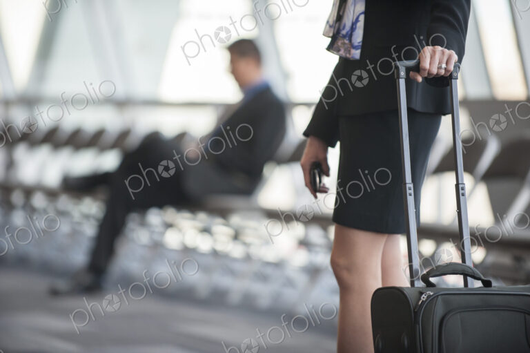 Close-up of a businesswoman's hands on the handle of a luggage carrier in a conference…