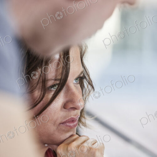 Close-up of a caucasian woman in an office meeting and a colleague standing over her. Close-up of a caucasian woman in an office meeting and a colleague standing over her.
