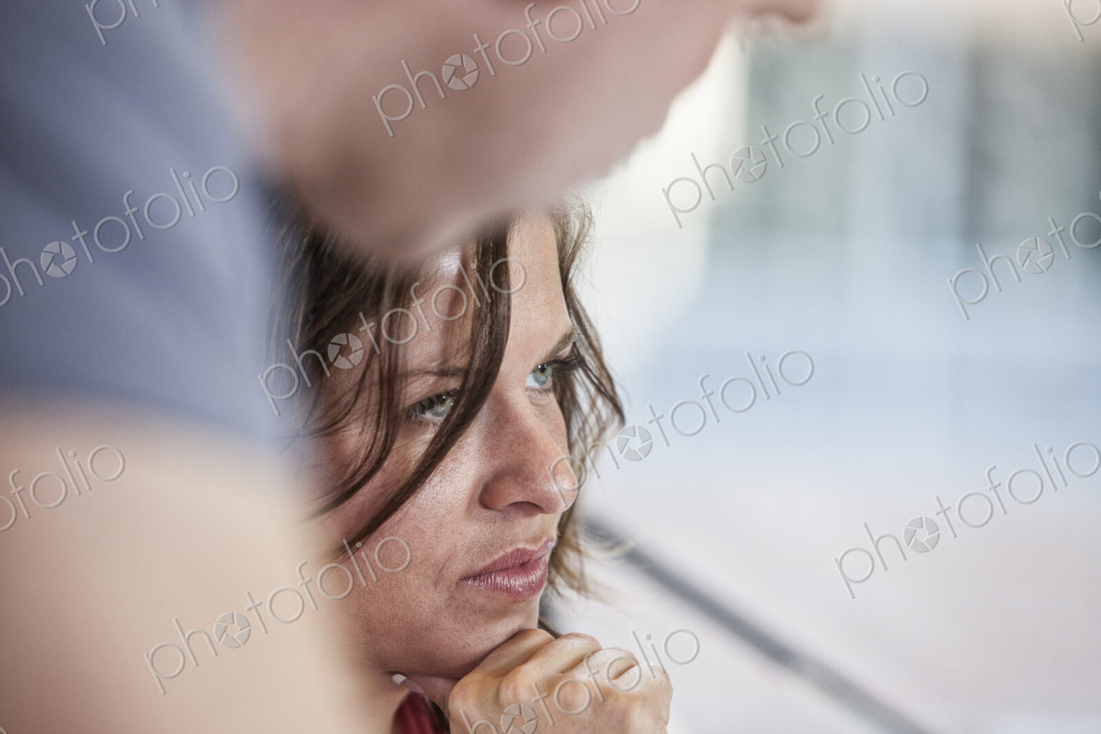 Close-up of a caucasian woman in an office meeting and a colleague standing over her.