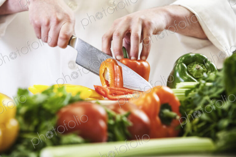 Close-up of a chef using a knife to chop fresh produce, colourful vegetables and bell…