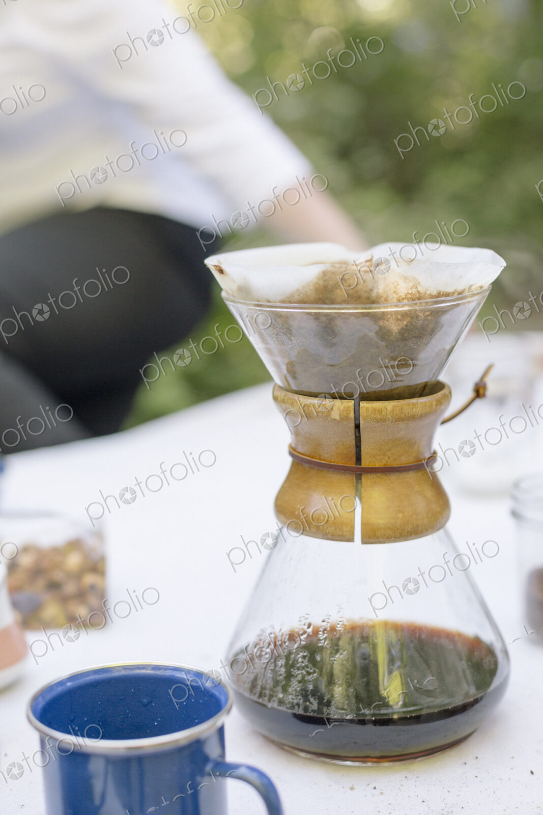 Close up of a glass coffee maker on a table in a garden.