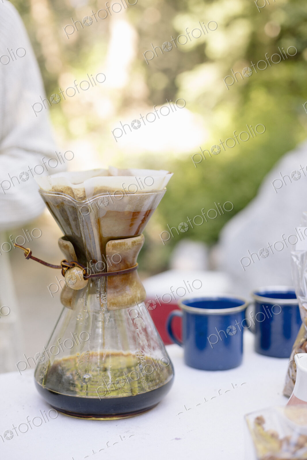 Close up of a glass coffee maker on a table in a garden.