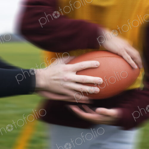 Close up of a hand off of a football in a game of non-contact flag football. Close up of a hand off of a football in a game of non-contact flag football.