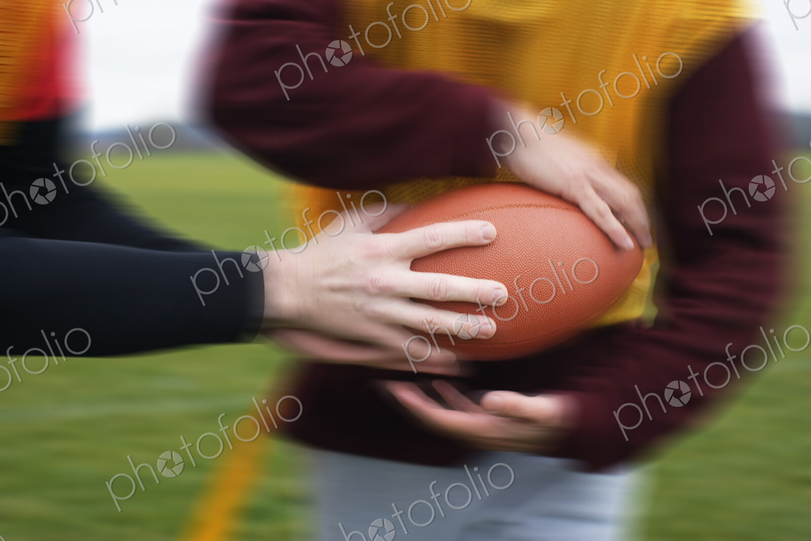 Close up of a hand off of a football in a game of non-contact flag football.