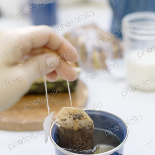 Close up of a hand removing a teabag from a mug of tea. Close up of a hand removing a teabag from a mug of tea.