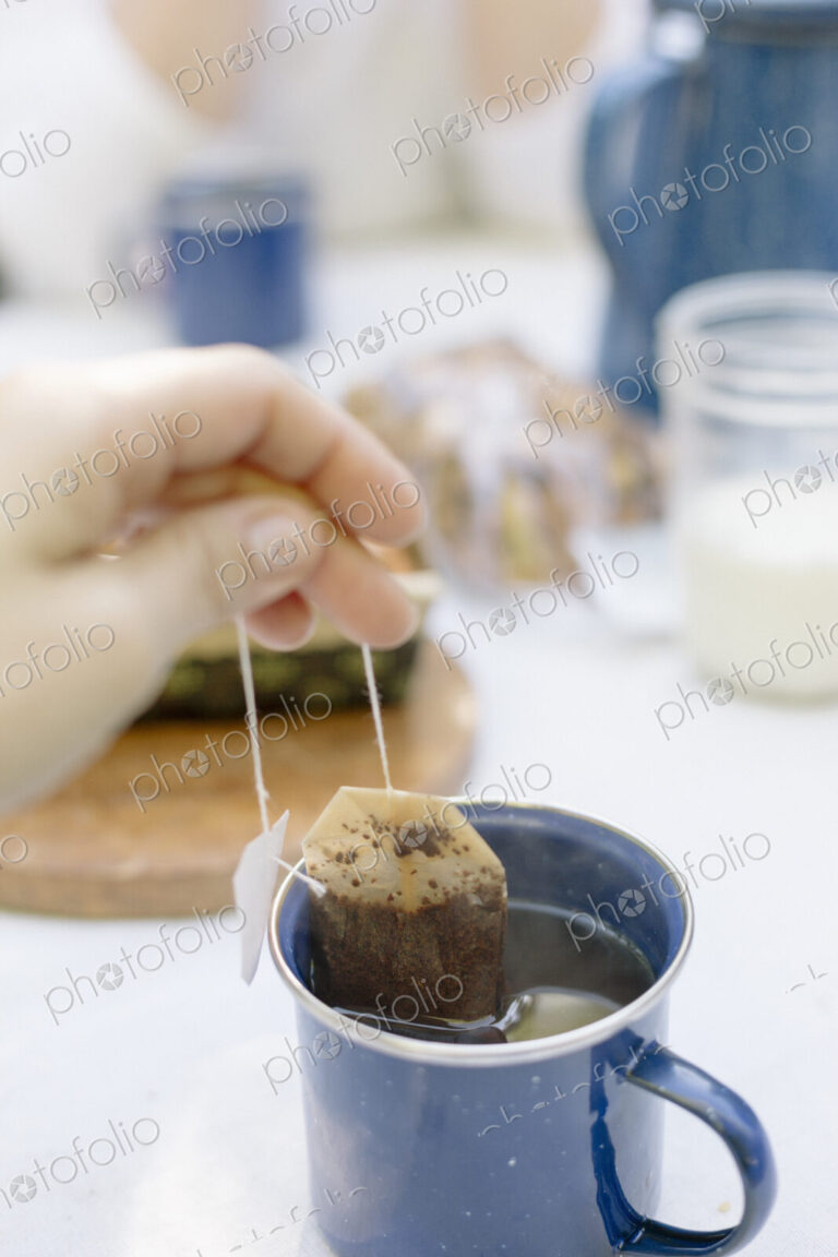 Close up of a hand removing a teabag from a mug of tea.