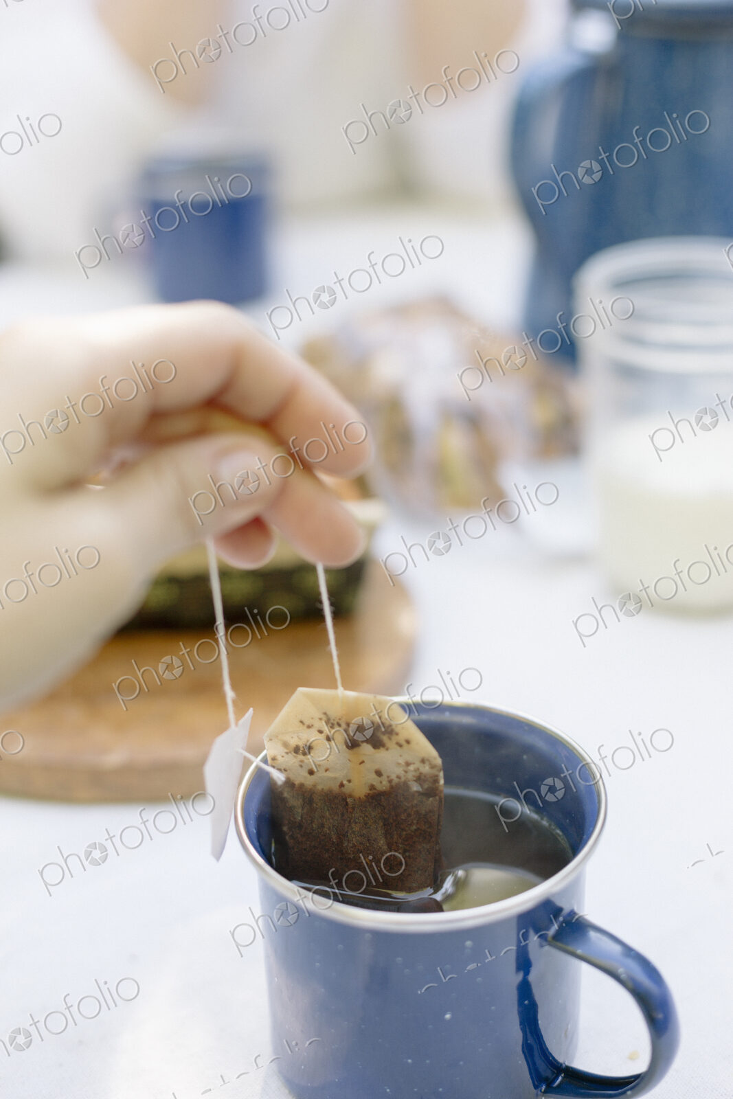 Close up of a hand removing a teabag from a mug of tea.