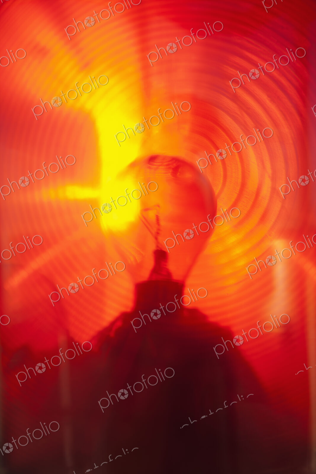 Close up of a lantern and lightbulb, radiating heat and light, red and yellow.