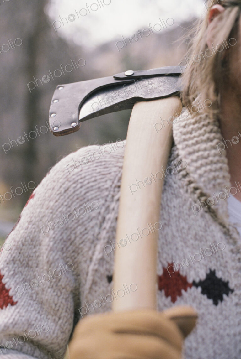 Close up of a man carrying an axe on his shoulder.