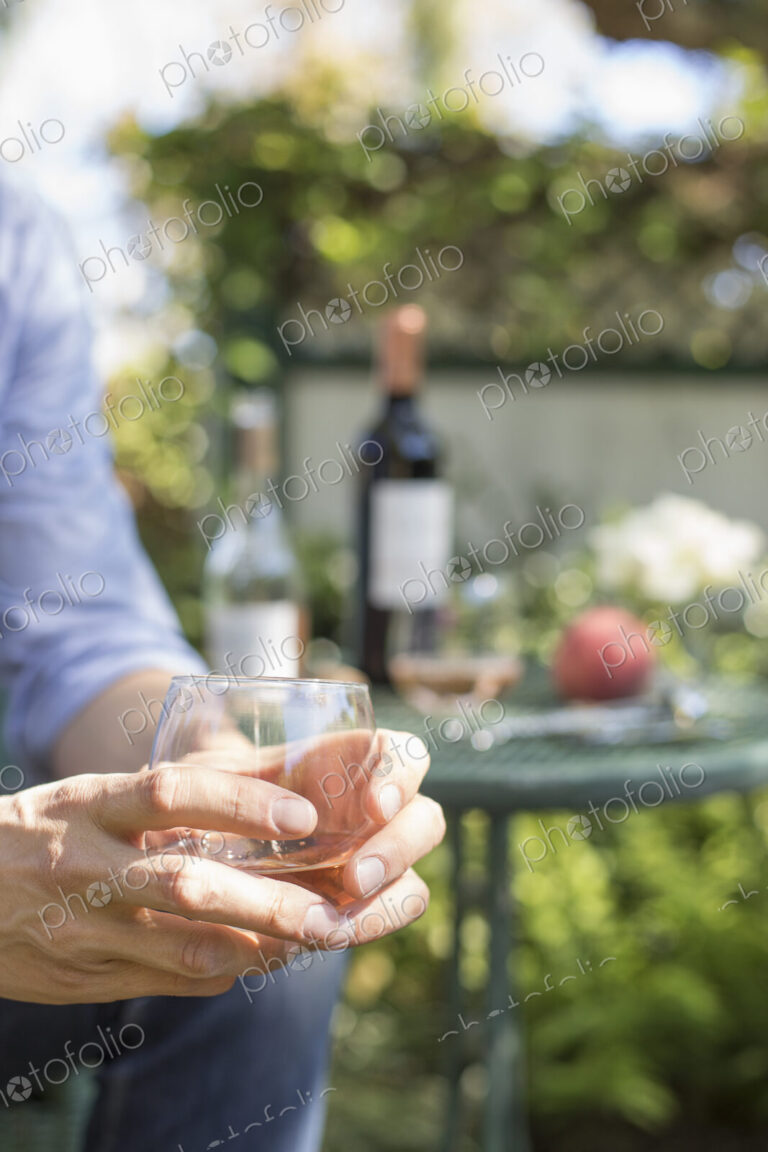 Close up of a man holding a glass of rose wine.
