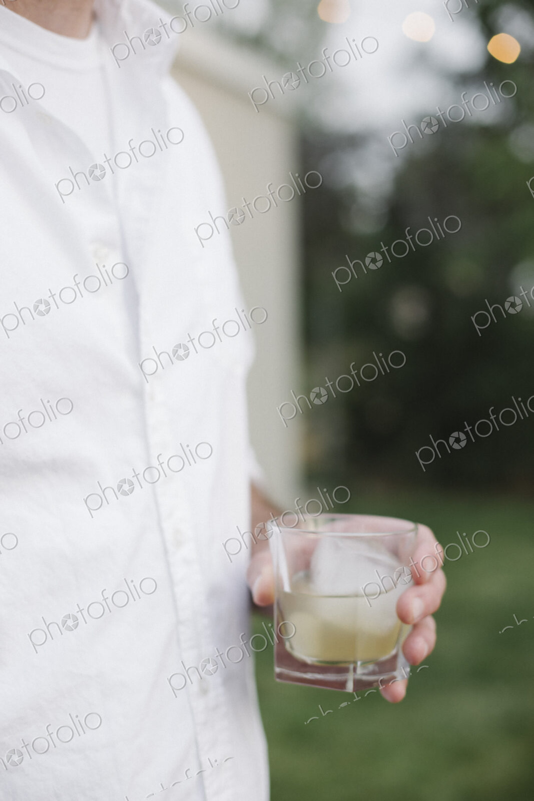 Close up of a man standing in a garden, holding a drink.