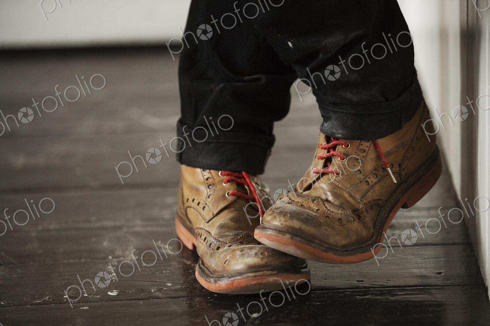 Close up of a man’s feet, wearing brown brogues with red shoe laces.
