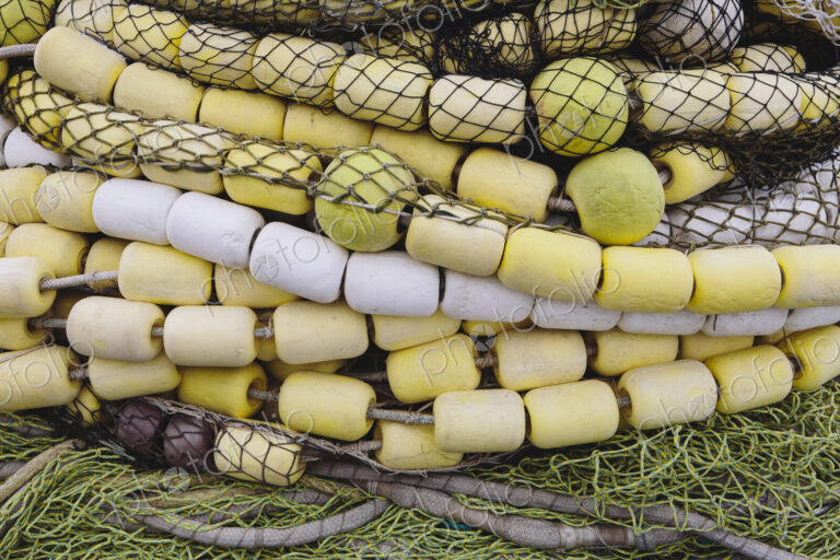 Close up of a pile of tangled up commercial fishing nets with floats attached.