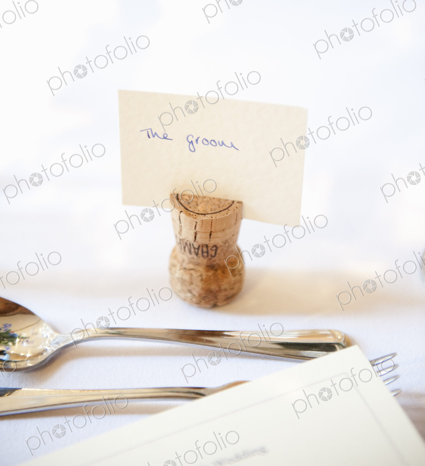 Close up of a place setting at the top table at a wedding banquet. An upside down cork…