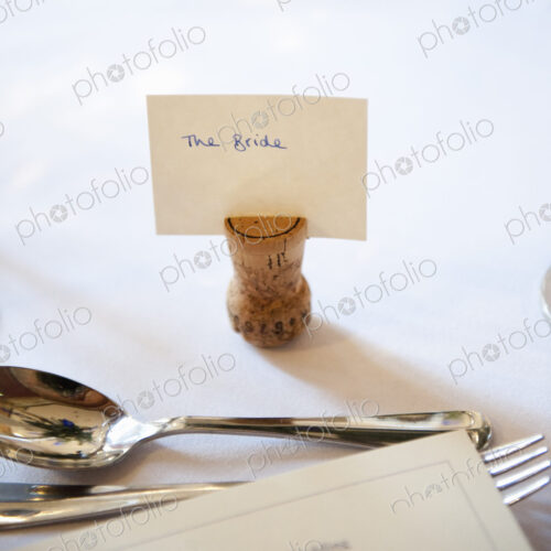 Close up of a place setting on the top table at a wedding banquet. An upside down cork… Close up of a place setting on the top table at a wedding banquet. An upside down cork…