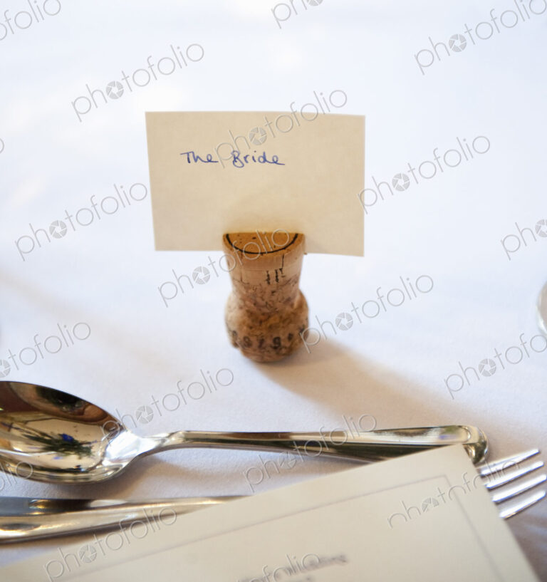 Close up of a place setting on the top table at a wedding banquet. An upside down cork…