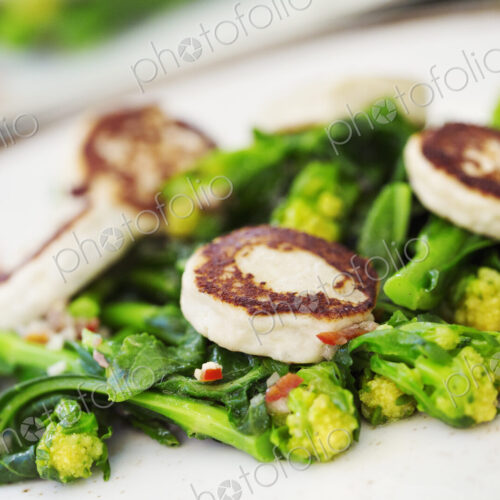 Close up of a plate of food, scallops and green vegetables.