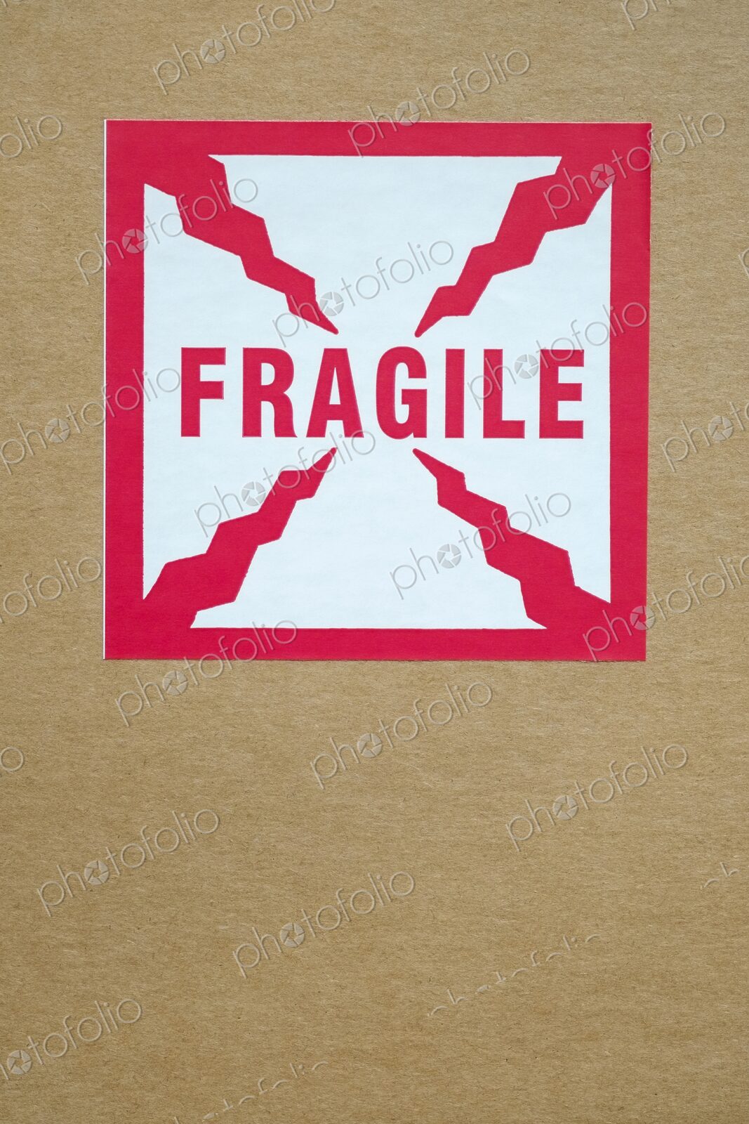 Close-up of a red and white “Fragile” sticker with crack-like graphic elements on a…
