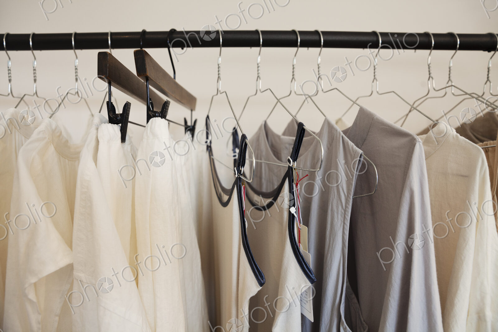 Close up of a selection of clothes in natural colours on a rail in a boutique.