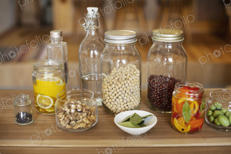 Close up of a selection of condiments and dried pulses in glass jars.
