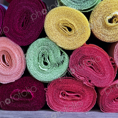 Close up of a selection of rolls of fabric in various colours.