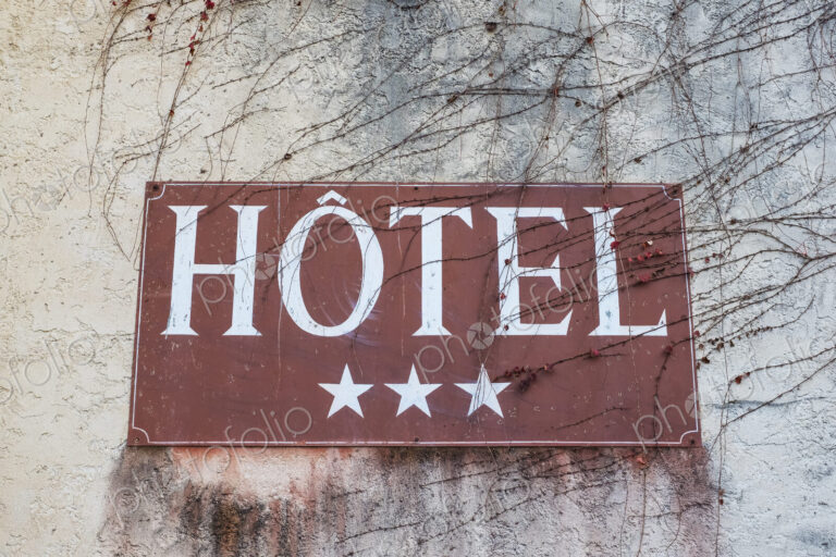 Close up of a three-star hotel sign on grey wall.