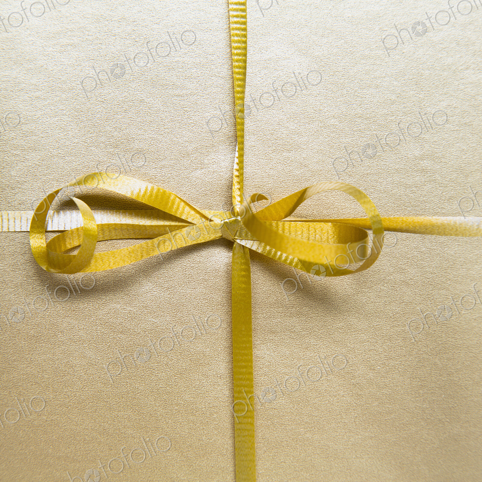Close up of a tied bow and gold ribbon from a wrapped gift.