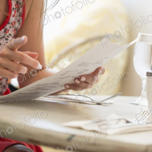 Close up of a woman at a restaurant table holding a menu.