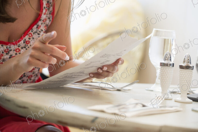 Close up of a woman at a restaurant table holding a menu.