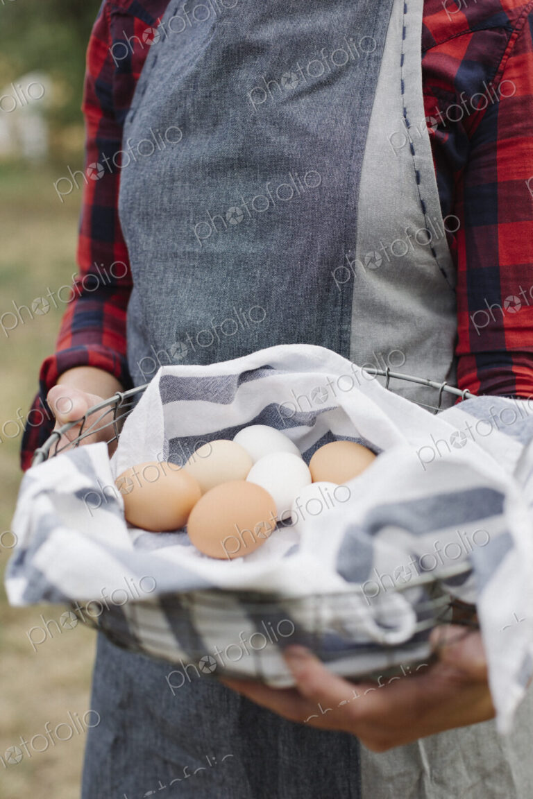Close up of a woman holding a bowl of fresh eggs.