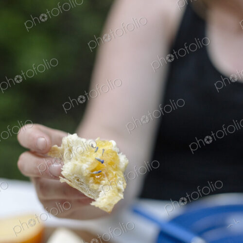 Close up of a woman holding a slice of white bread with jam.