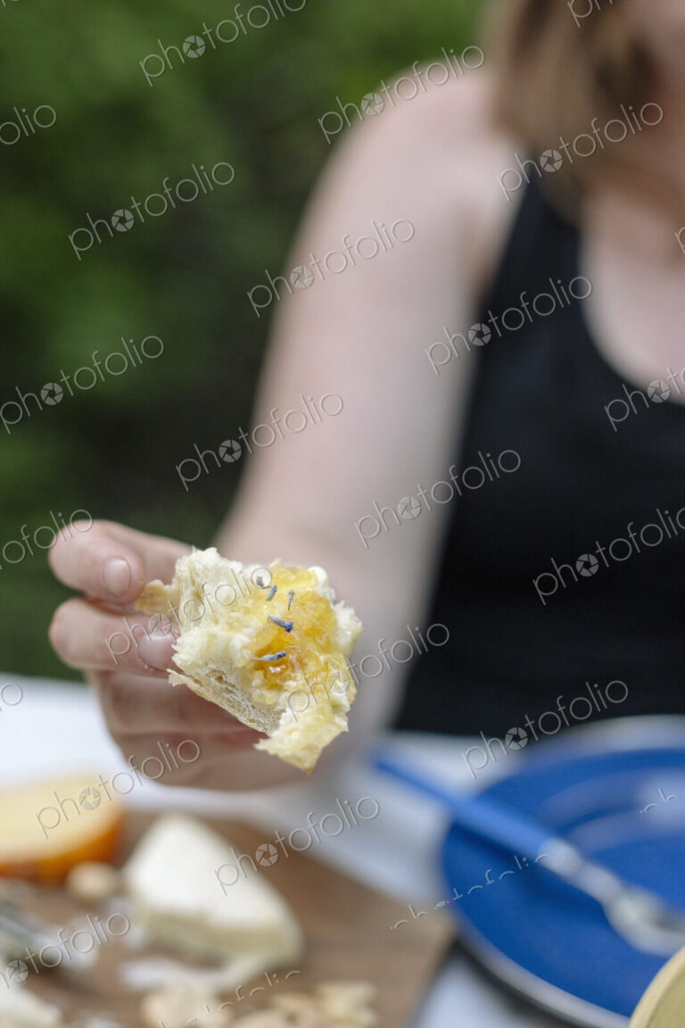 Close up of a woman holding a slice of white bread with jam.