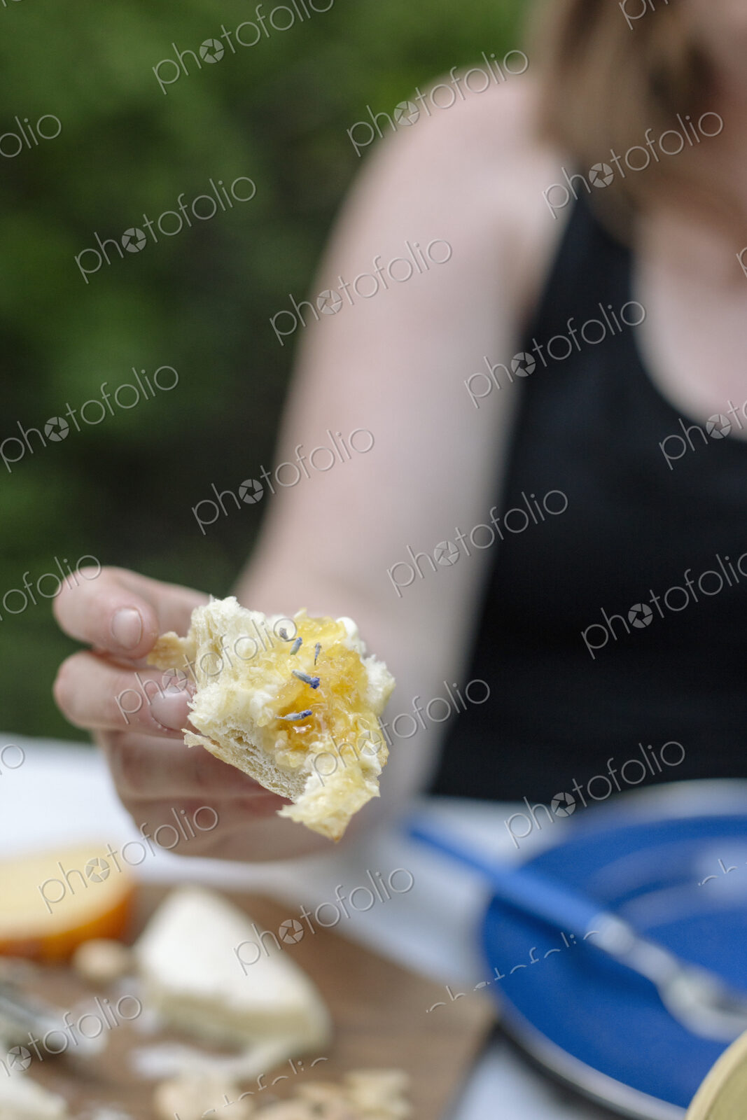 Close up of a woman holding a slice of white bread with jam.
