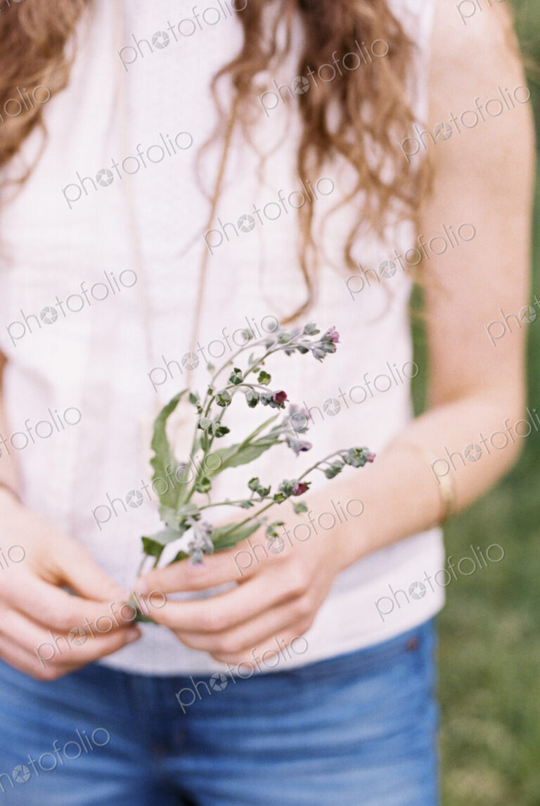 Close up of a woman holding a wild flower.